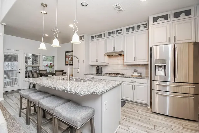 a kitchen with stainless steel appliances granite countertop a sink a stove a refrigerator and island with wooden floor