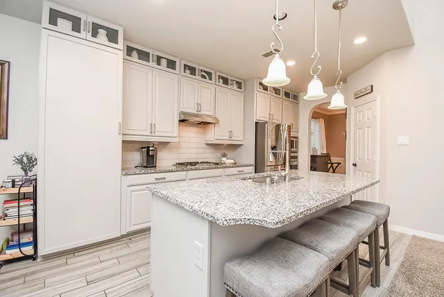 a kitchen with stainless steel appliances granite countertop a sink a stove and a refrigerator