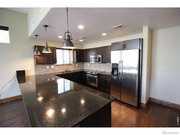 a kitchen with stainless steel appliances granite countertop a refrigerator a sink a stove and a microwave