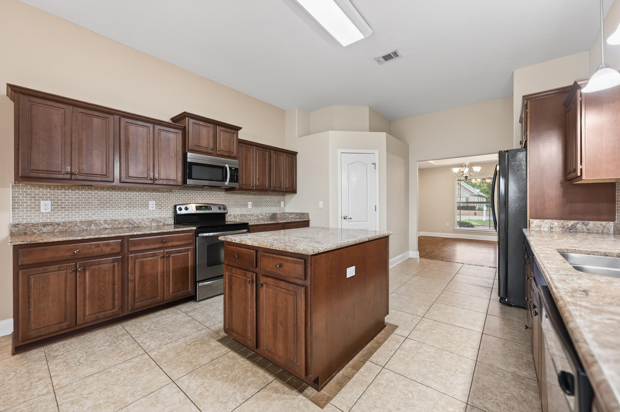 6210 Lapis Lane Crestview, FL 32539 - Photo 16 of 72 a kitchen with stainless steel appliances granite countertop a stove top oven a sink dishwasher and a refrigerator with wooden cabinets