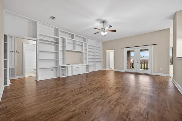 a view of an empty room with a window and wooden floor