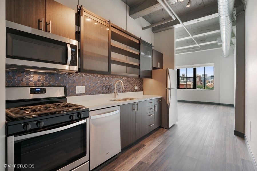 2101 South Wabash Avenue, Unit 402 Chicago, IL 60616 - Photo 3 of 9 a kitchen with stainless steel appliances kitchen island granite countertop a stove and a microwave