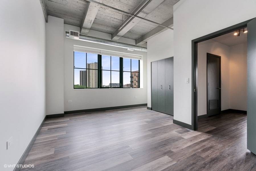 2101 South Wabash Avenue, Unit 402 Chicago, IL 60616 - Photo 5 of 9 an empty room with wooden floor and windows