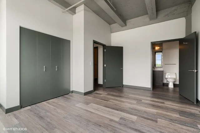 a view of an empty room with wooden floor and a bathroom