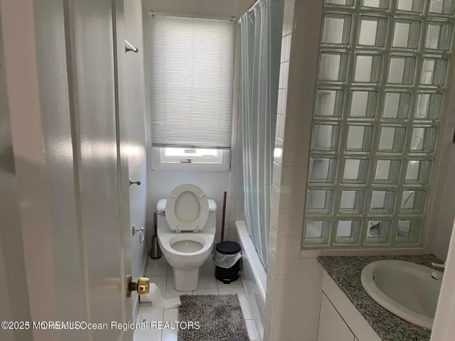 a bathroom with a granite countertop sink and a toilet