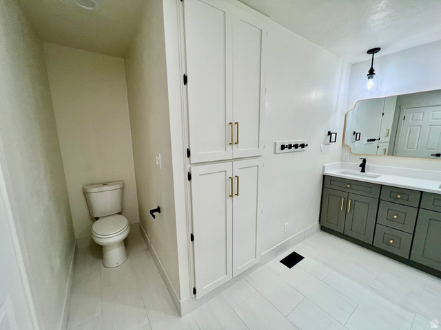 812 East Bates Cyn Road Tooele, UT 84074 - Photo 45 of 144 Bathroom featuring white tile flooring, a dual-sink vanity with gray cabinetry and gold-tone hardware, a decorative mirror, and an adjacent built-in storage cabinet with gold-tone hardware
