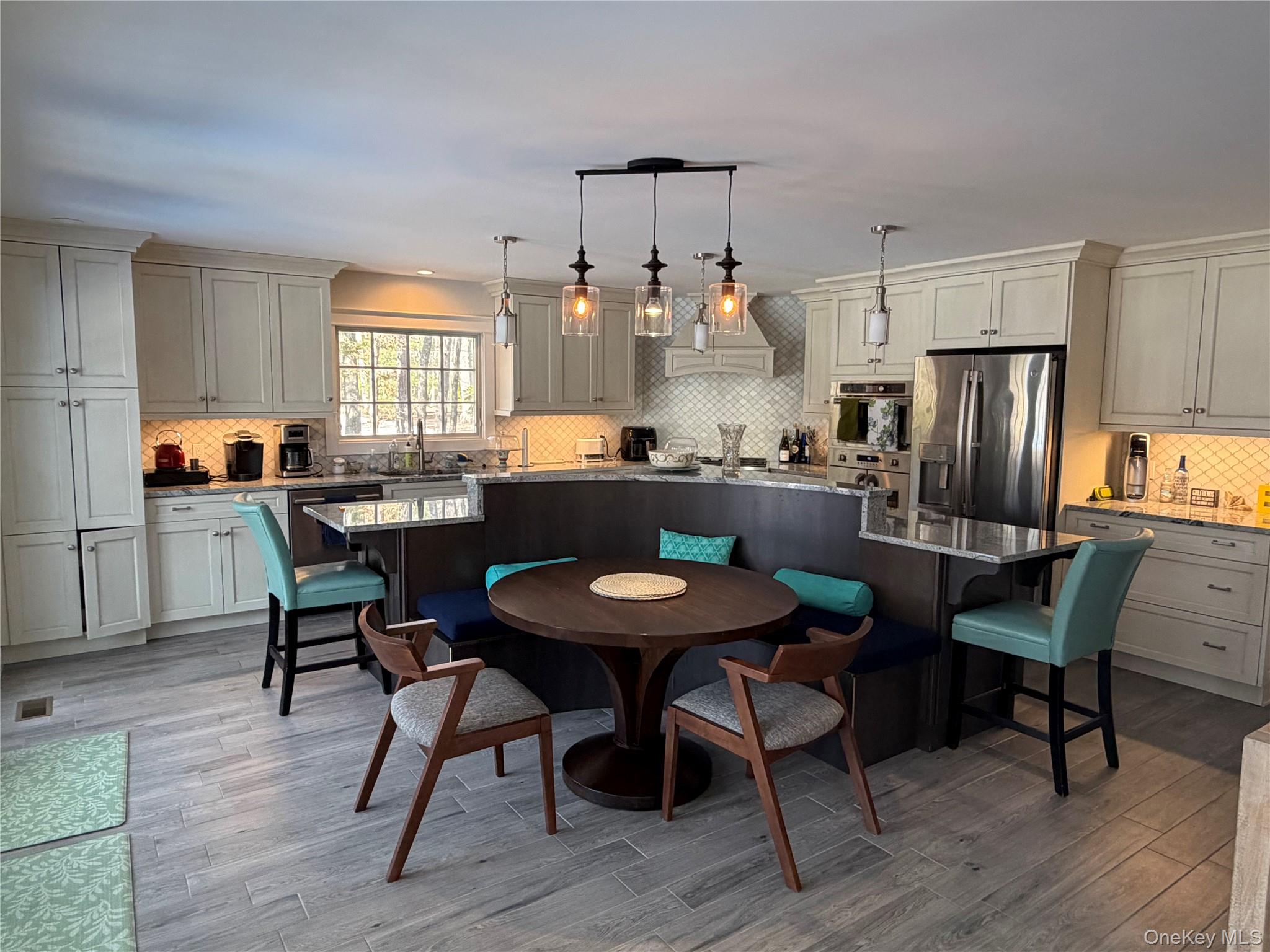 27 Deer Path Quogue, NY 11959 - Photo 13 of 44 a kitchen with stainless steel appliances kitchen island granite countertop a dining table chairs and a refrigerator