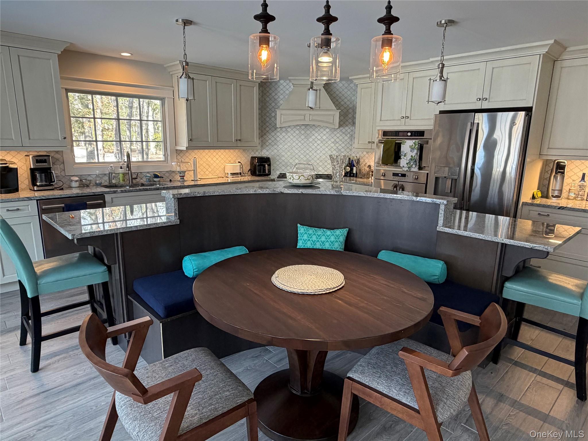 27 Deer Path Quogue, NY 11959 - Photo 14 of 44 a kitchen with stainless steel appliances granite countertop a dining table chairs and a refrigerator