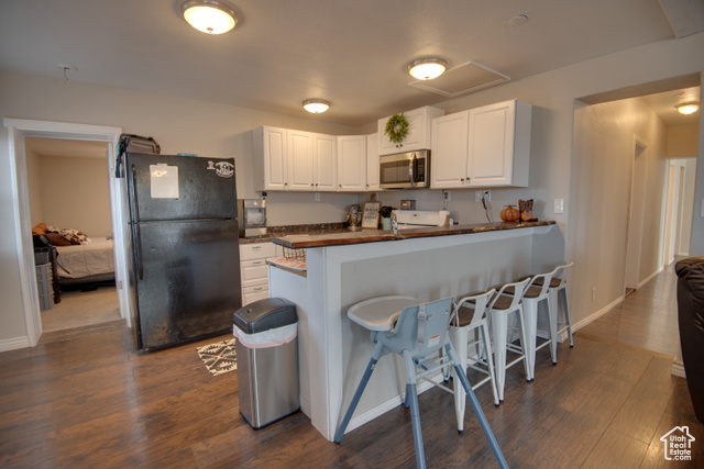 410 North Main Street Beaver, UT 84713 - Photo 14 of 31 Kitchen with a breakfast bar, black refrigerator, white cabinets, and dark hardwood / wood-style floors