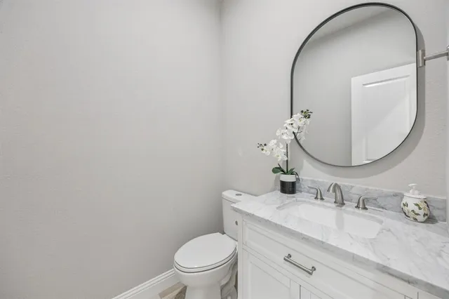 a bathroom with a granite countertop toilet a sink and a mirror