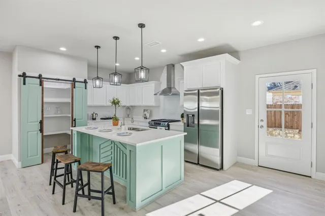 a kitchen with stainless steel appliances kitchen island a table chairs refrigerator and sink
