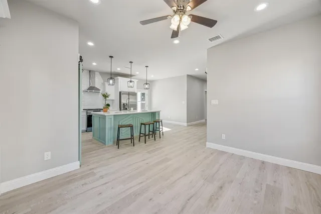 an empty room with kitchen and chandelier fan