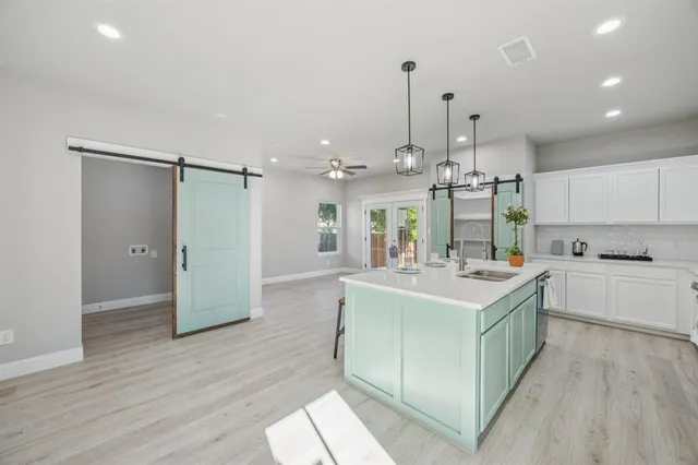 a large kitchen with kitchen island a island wooden floor and stainless steel appliances