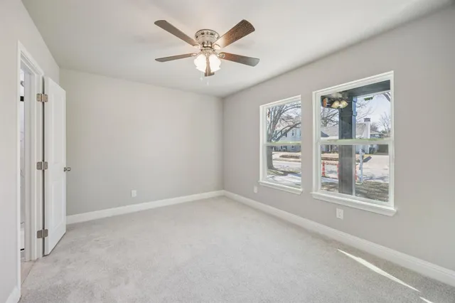 an empty room with windows and ceiling fan