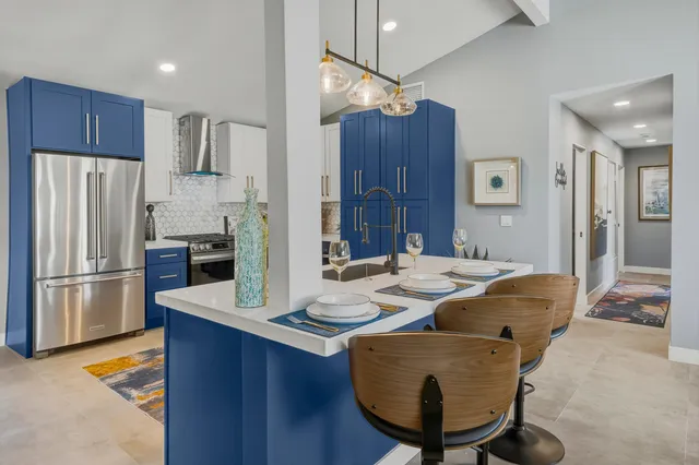 a kitchen with stainless steel appliances kitchen island granite countertop a refrigerator a stove a sink and a dining table with wooden floor