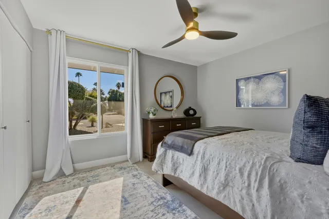 a bedroom with a bed a mirror on dresser and a window