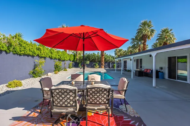 a view of a patio with a table and chairs under an umbrella