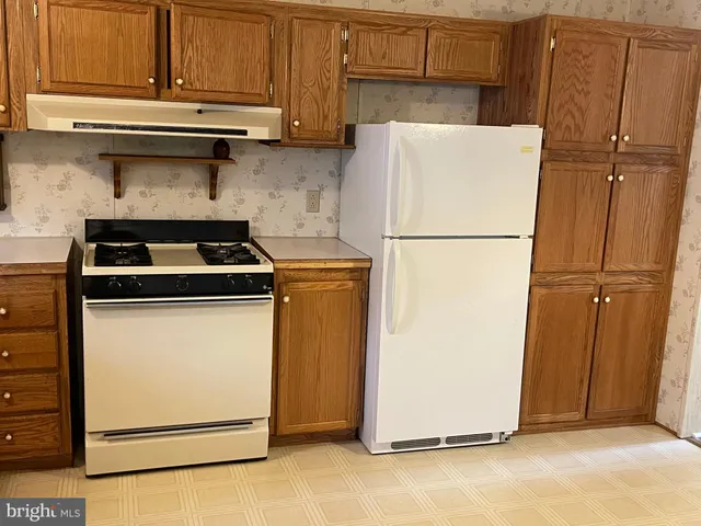 a white refrigerator freezer and a stove sitting inside of a kitchen