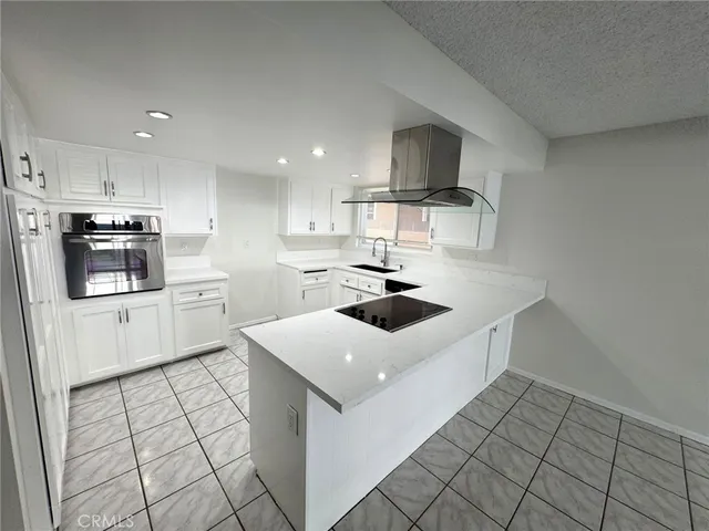 a kitchen with a sink a stove top oven and white cabinets
