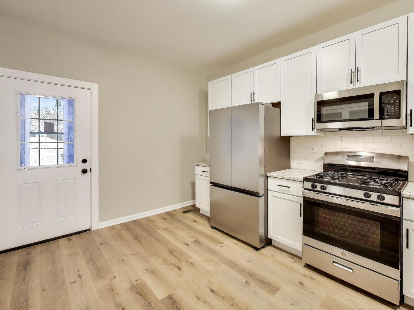 4213 West Roscoe Street, Unit 1 Chicago, IL 60641 - Photo 6 of 15 a kitchen with stainless steel appliances white cabinets and wooden floor