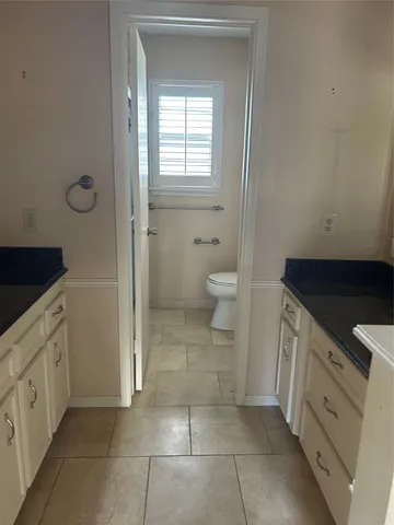 a bathroom with a granite countertop sink a toilet and a vanity
