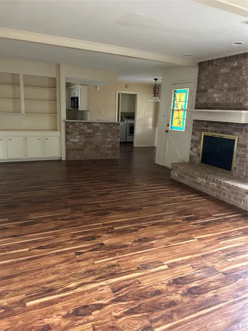 a view of a livingroom with wooden floor and a fireplace