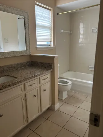 a bathroom with a granite countertop toilet sink and mirror