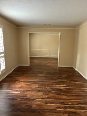 an empty room with wooden floor and windows with curtains