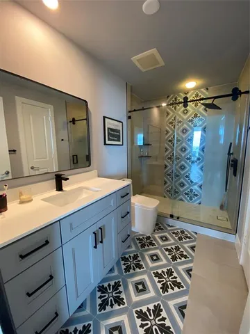 a bathroom with a sink a toilet a mirror a vanity and shower