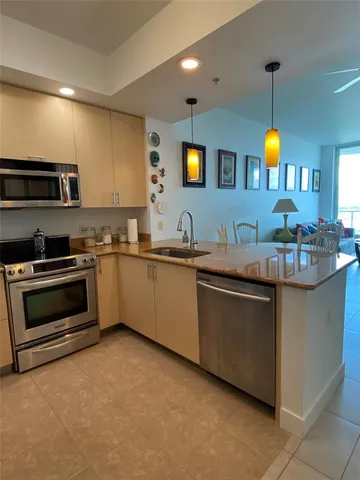 a kitchen with kitchen island granite countertop a sink a counter top space stove and cabinets