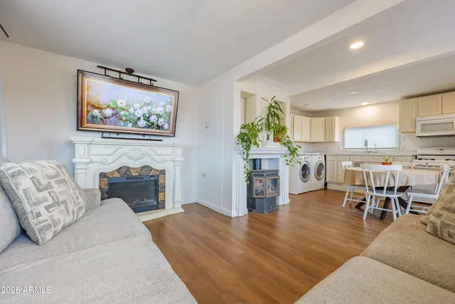 a living room with furniture a fireplace and a kitchen view