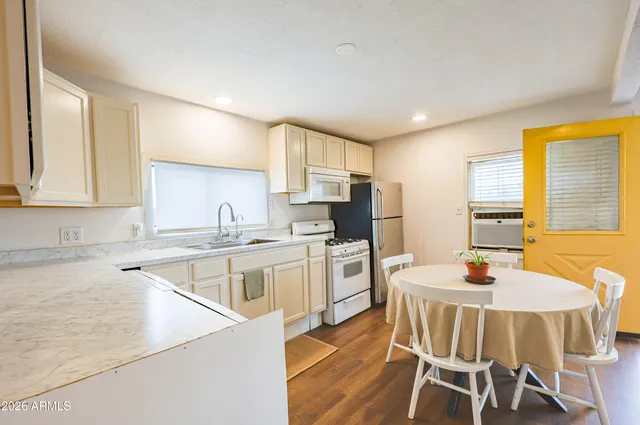 a kitchen with a stove a sink a kitchen island with chairs and wooden cabinets