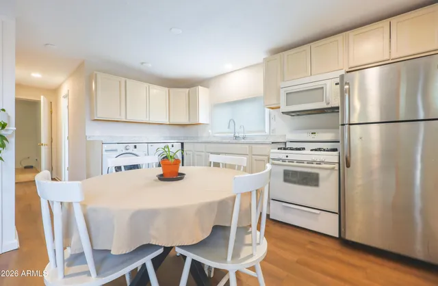 a kitchen with stainless steel appliances a refrigerator a stove a sink and white cabinets with wooden floor