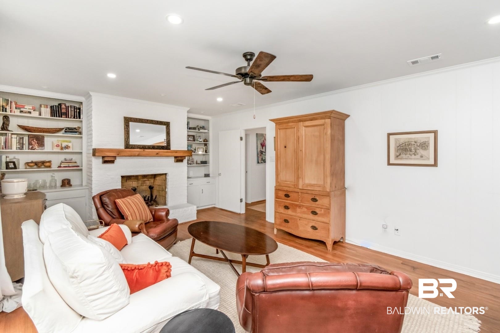 4596 Hawthorne Place Mobile, AL 36608 - Photo 23 of 34 Living room with hardwood flooring, painted brick fireplace with wood mantel, built-in shelving, and a ceiling fan
