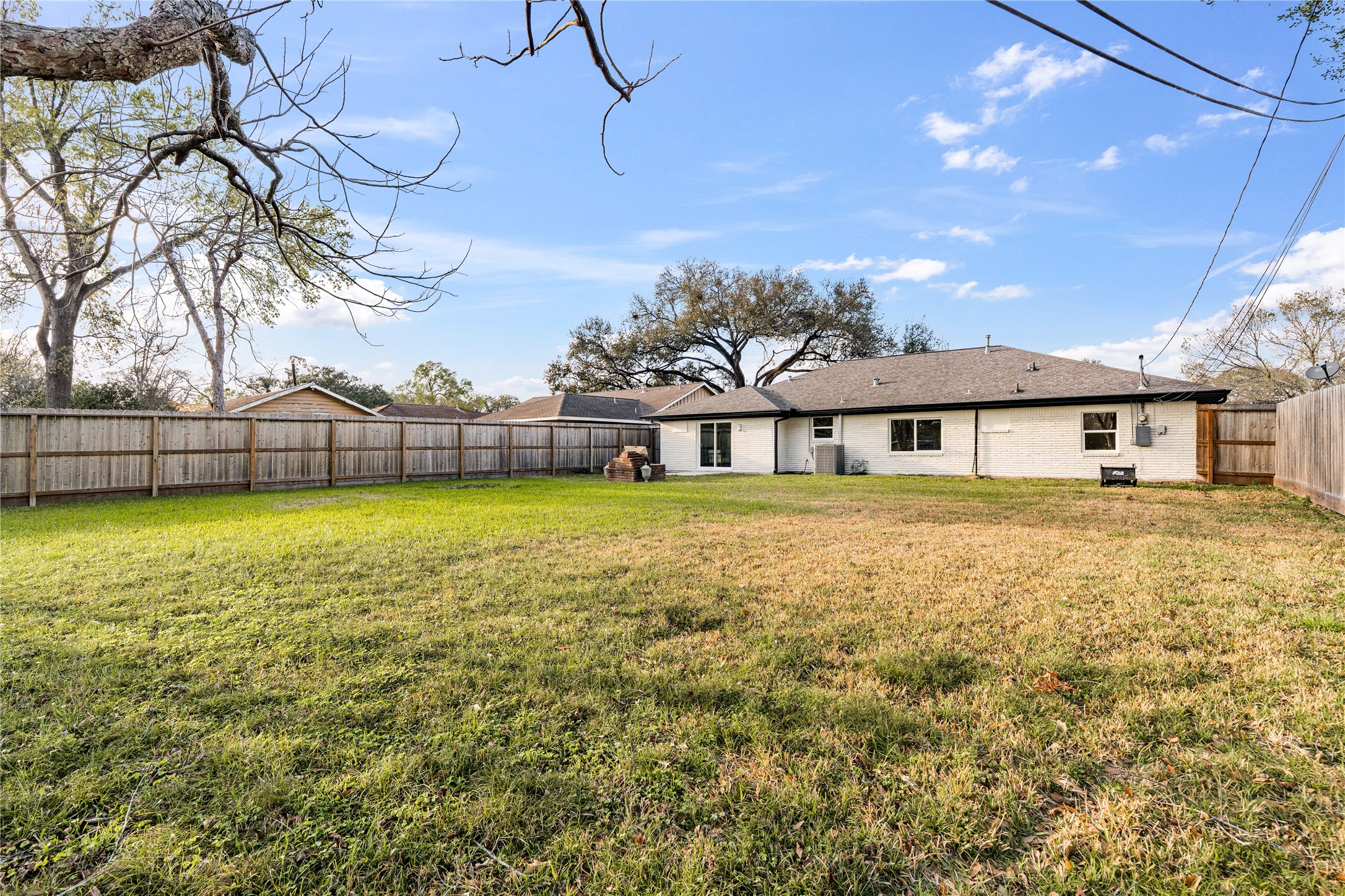 5023 Redstart Street Houston, TX 77035 - Photo 33 of 34 The massive private lot is fully enclosed by a sturdy wooden fence, providing a vast grassy area shaded by mature trees for outdoor enjoyment.