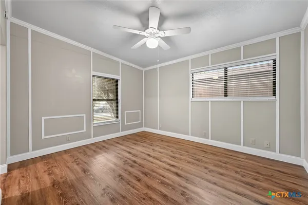 a view of an empty room with a window and wooden floor
