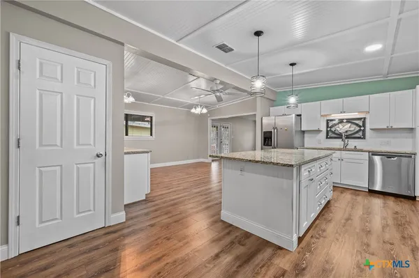 a kitchen with stainless steel appliances granite countertop a white cabinets and wooden floors