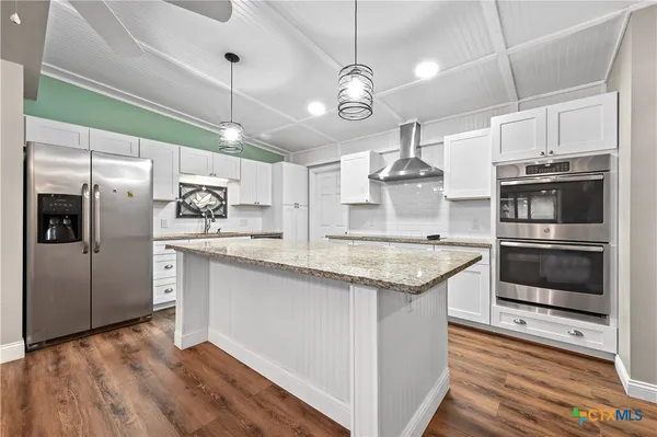a kitchen with kitchen island granite countertop a sink stainless steel appliances and cabinets