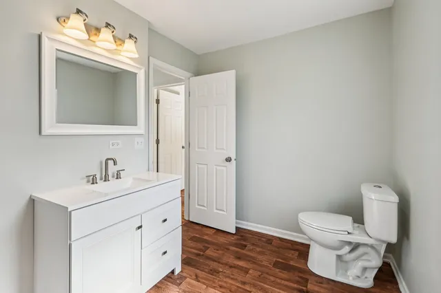 a bathroom with a toilet sink vanity and mirror