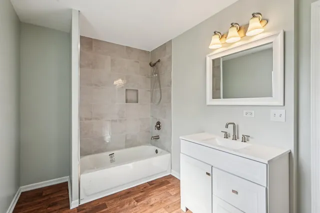 a bathroom with a sink a bathtub a mirror a vanity and a shower