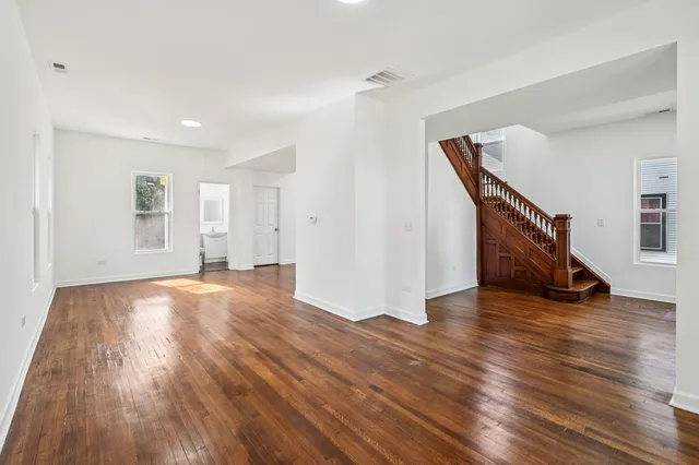 a view of an empty room with wooden floor and stairs