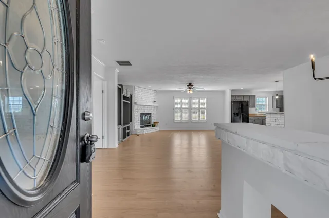 a view of an empty room with chandelier and wooden floor