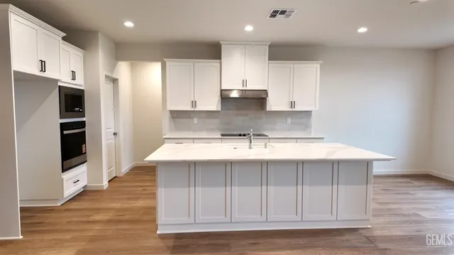 a view of kitchen with stainless steel appliances granite countertop a stove and a refrigerator