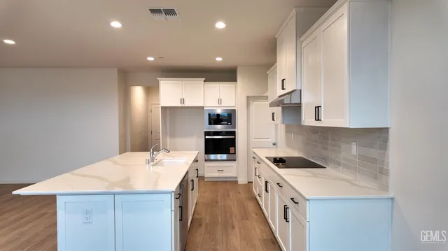 a kitchen with stainless steel appliances kitchen island granite countertop a refrigerator and a stove top oven