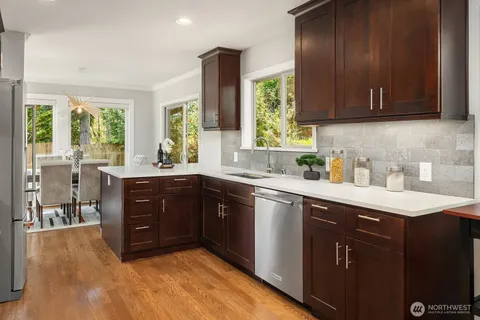 a kitchen with stainless steel appliances granite countertop wooden cabinets a refrigerator a sink a stove and a microwave