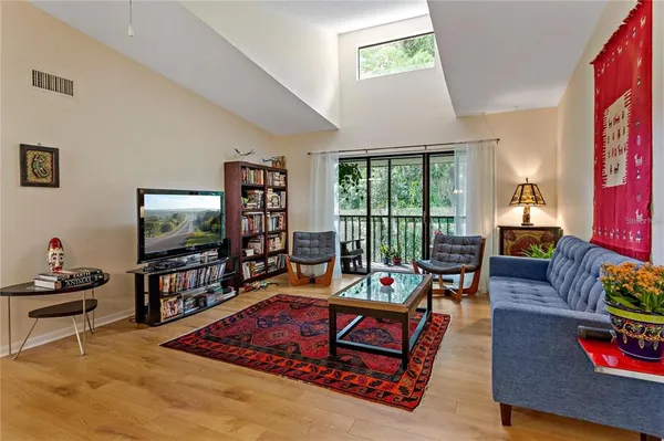 a living room with furniture a flat screen tv and a floor to ceiling window