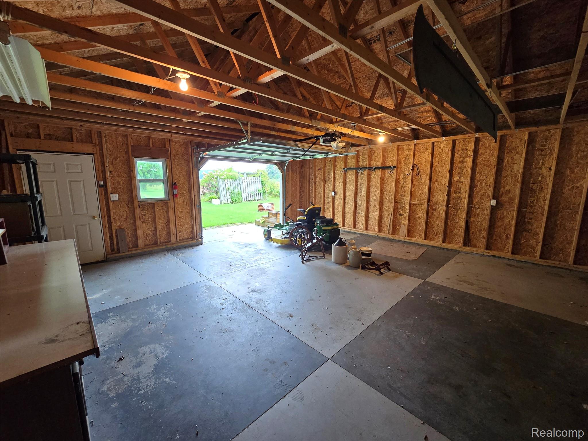 5282 McIntyre Road North Street, MI 48049 - Photo 53 of 53 Spacious garage with exposed wood rafters, checkerboard concrete flooring, and a single-panel interior door