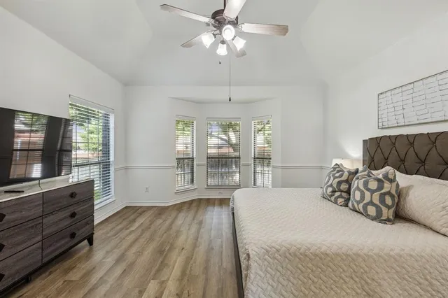 a spacious bedroom with a bed a dresser and flat screen tv