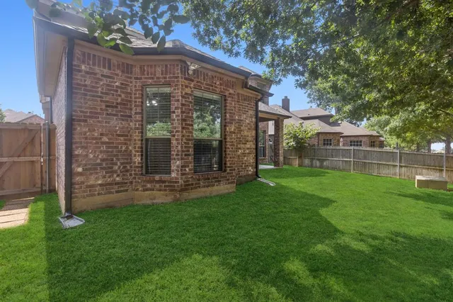 a brick house with a big yard and large trees