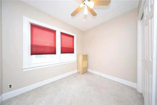 an empty room with windows and chandelier fan
